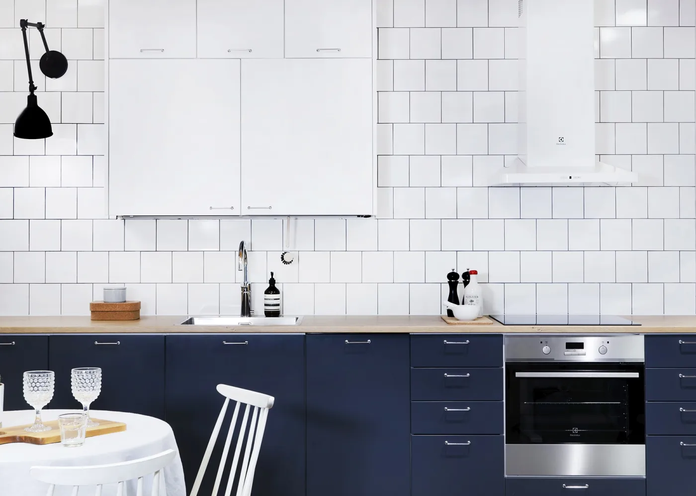 sinivalkoinen keittiö kromisilla lankavetimillä ja tammitasolla